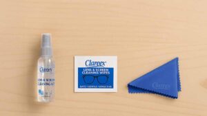 A digital photograph displays Clareex Trifecta, a 3-step screen cleaning system, with spray bottle, cleaning wipe sachet, and microfiber cloth on a light wood surface.